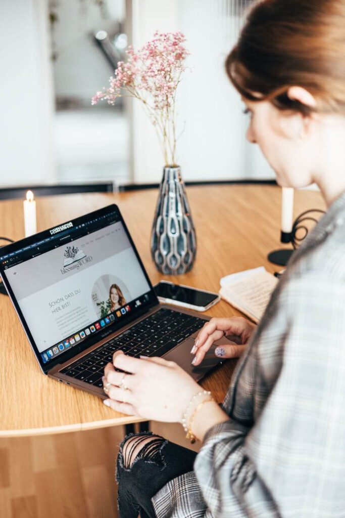 Frau schaute ihrem Businessfotoshooting ihre Webseite an und sitzt am Tisch.